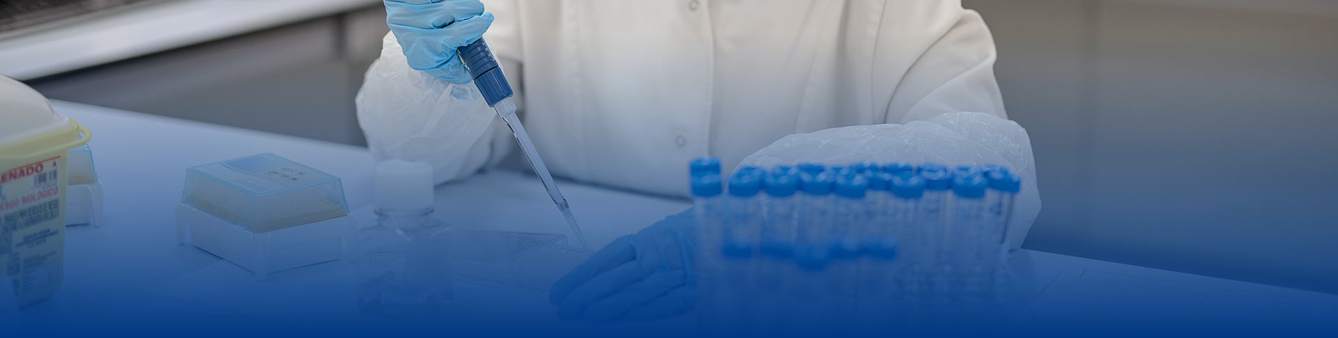 Un técnico de laboratorio con bata y guantes maniobrando pipetas en un laboratorio de Eurofins BioPharma Product Testing. La imagen muestra un entorno profesional y preciso, con el técnico realizando análisis en un ambiente controlado para garantizar la calidad y confiabilidad de los resultados en la investigación farmacéutica.