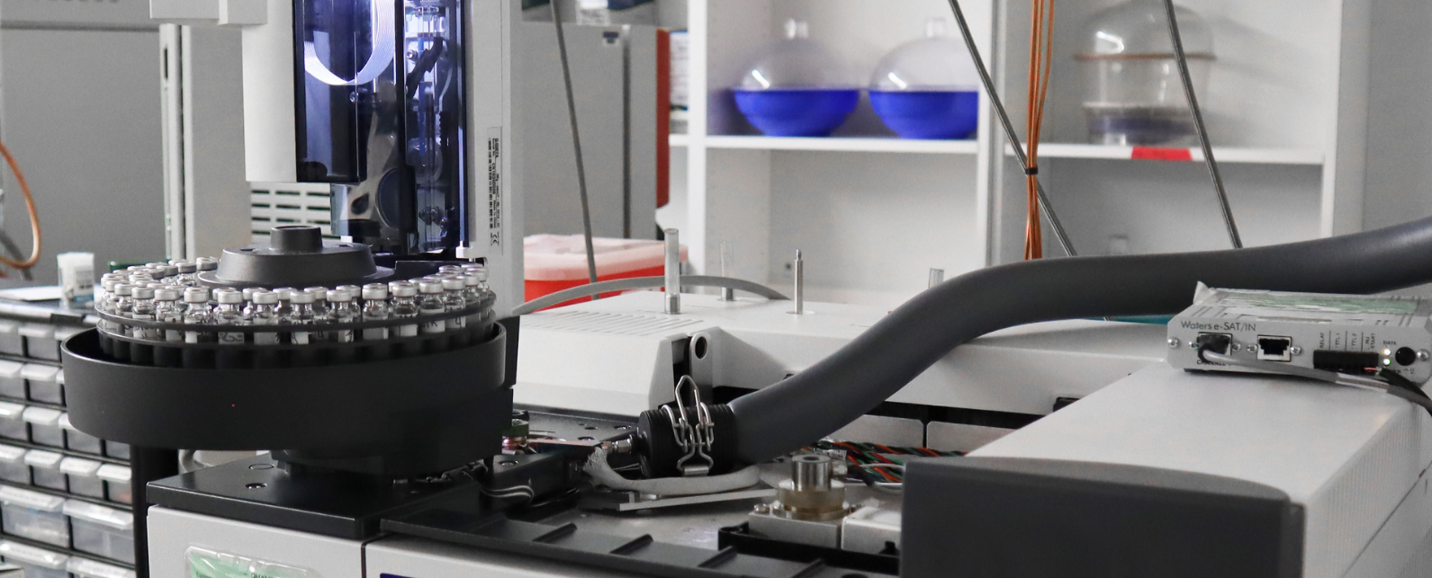 A hand is placing one vial onto a round tray full of additional vials for testing,