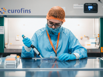 Un técnico de laboratorio con guantes, bata y cofia para el cabello, realizando análisis para evaluar la eficacia de desinfectantes en un laboratorio de Eurofins BioPharma Product Testing. Utilizando equipos especializados, el técnico verifica la capacidad del desinfectante para eliminar microorganismos, asegurando la efectividad y seguridad de los productos en el ámbito farmacéutico.